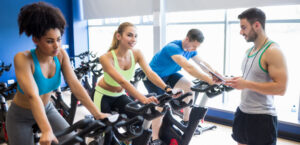 Groep mensen neemt deel aan een spinningles tijdens de wereldfietsdagen 2025, onder begeleiding van een instructeur in een fitnesscentrum.
