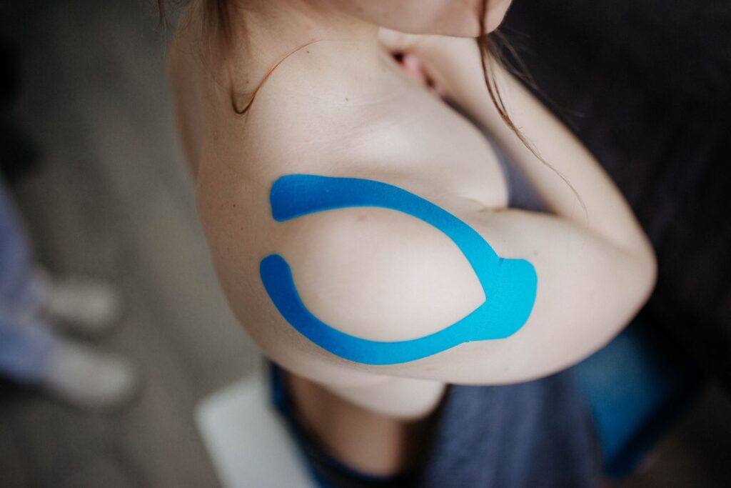 Blauwe kinesiologische tape op de schouder — medical taping