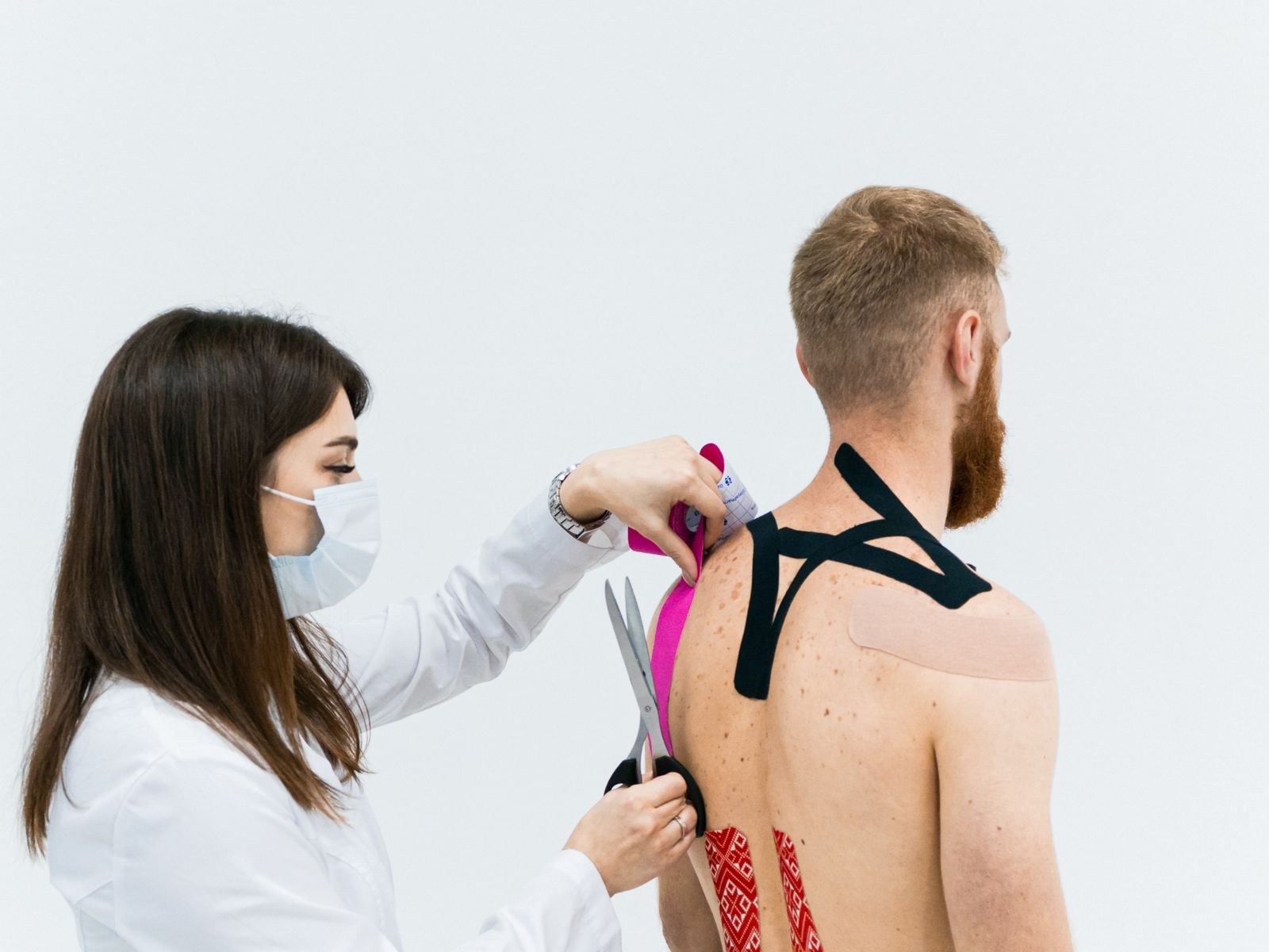 Therapeut brengt kinesiotape aan op de rug