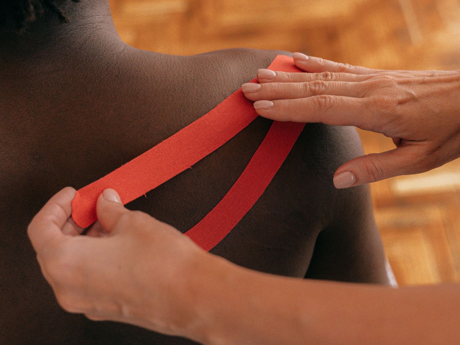 Therapeut brengt rode medical tape aan op de schouder