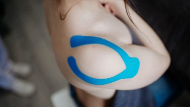 Blauwe kinesiologische tape op de schouder — medical taping