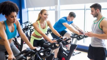 Groep mensen neemt deel aan een spinningles tijdens de wereldfietsdagen 2025, onder begeleiding van een instructeur in een fitnesscentrum.